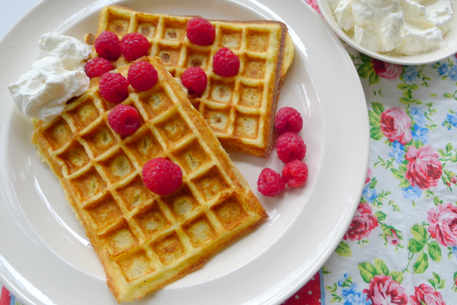 twee wafels op een bord met slagroom en frambozen